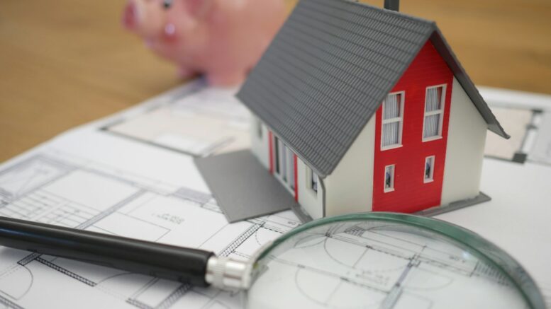 white and red wooden house beside grey framed magnifying glass